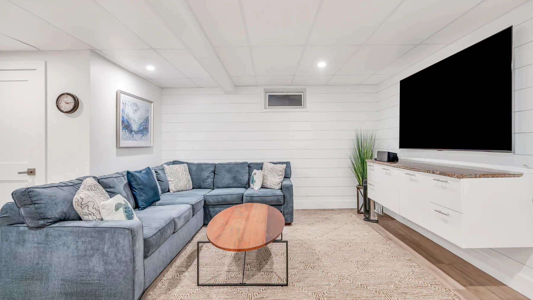 A living room with a sectional seating area, coffee table, and wall-mounted television.