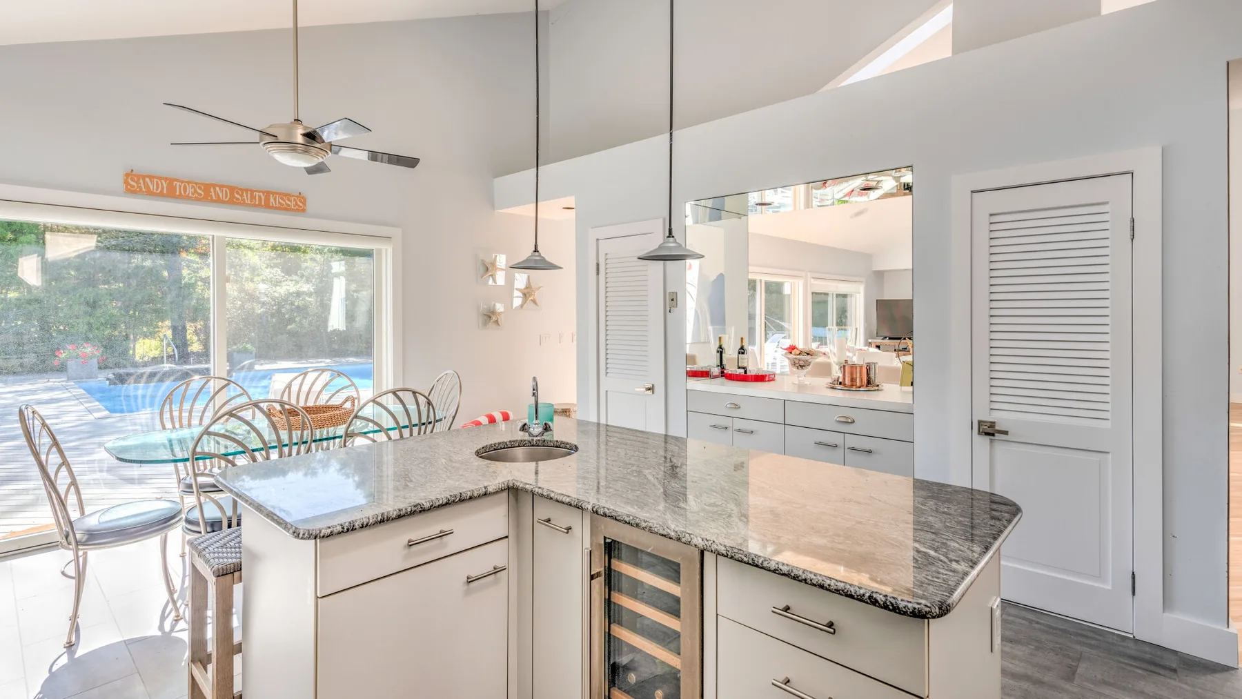 A bright kitchen with a central island and a dining area beside large windows.