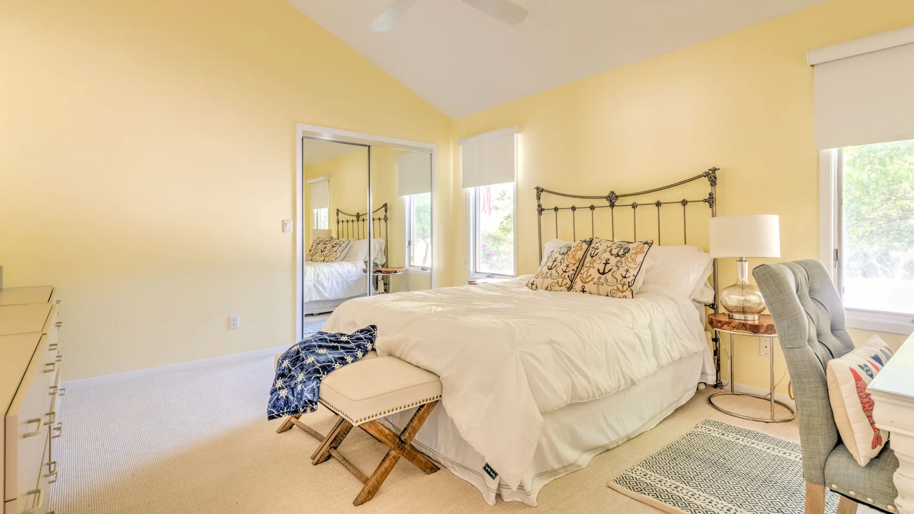 A bright bedroom with a bed, bedside table, and windows.