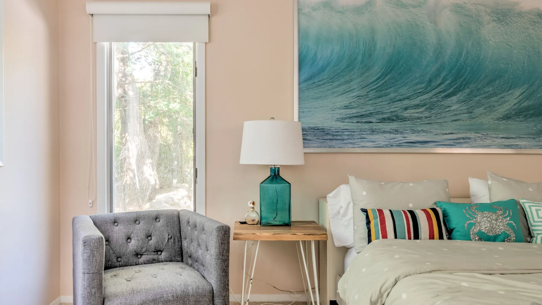 A bedroom with a bed, bedside table, and gray upholstered seating.