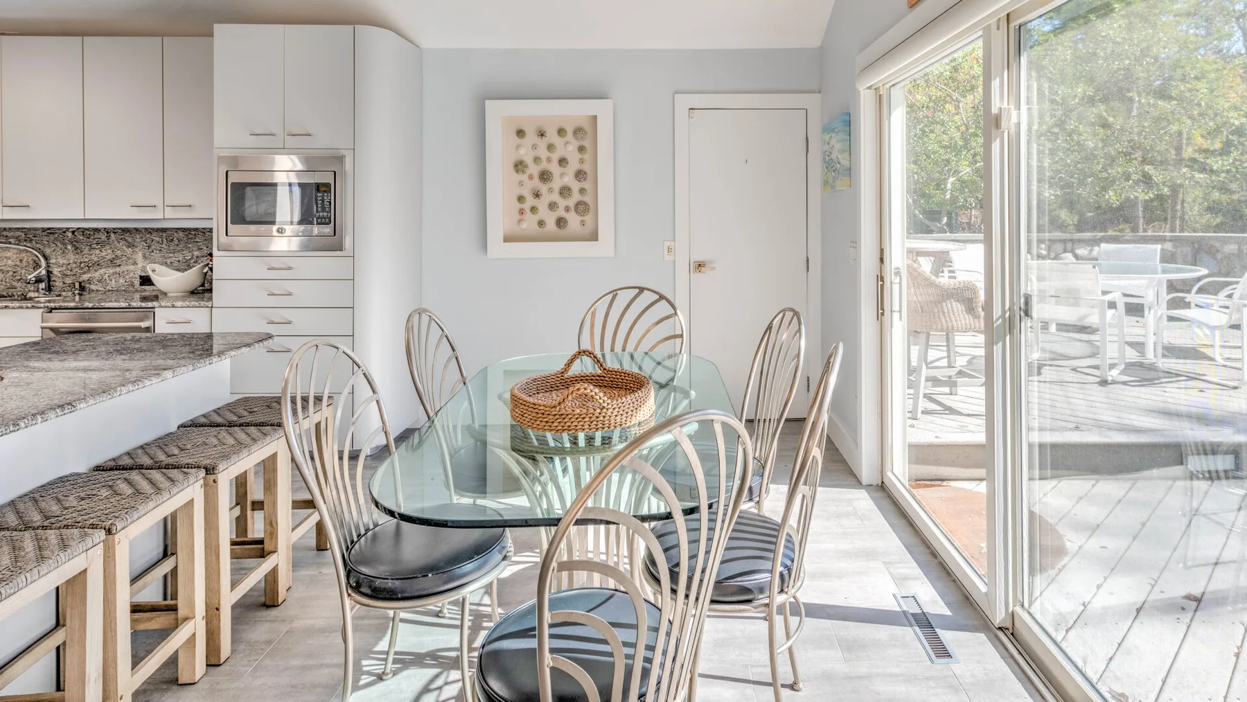 A bright kitchen and dining area opens onto a deck through large glass doors.
