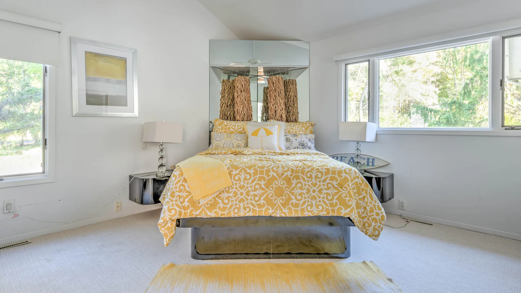 A bright bedroom with a bed dressed in yellow patterned bedding.