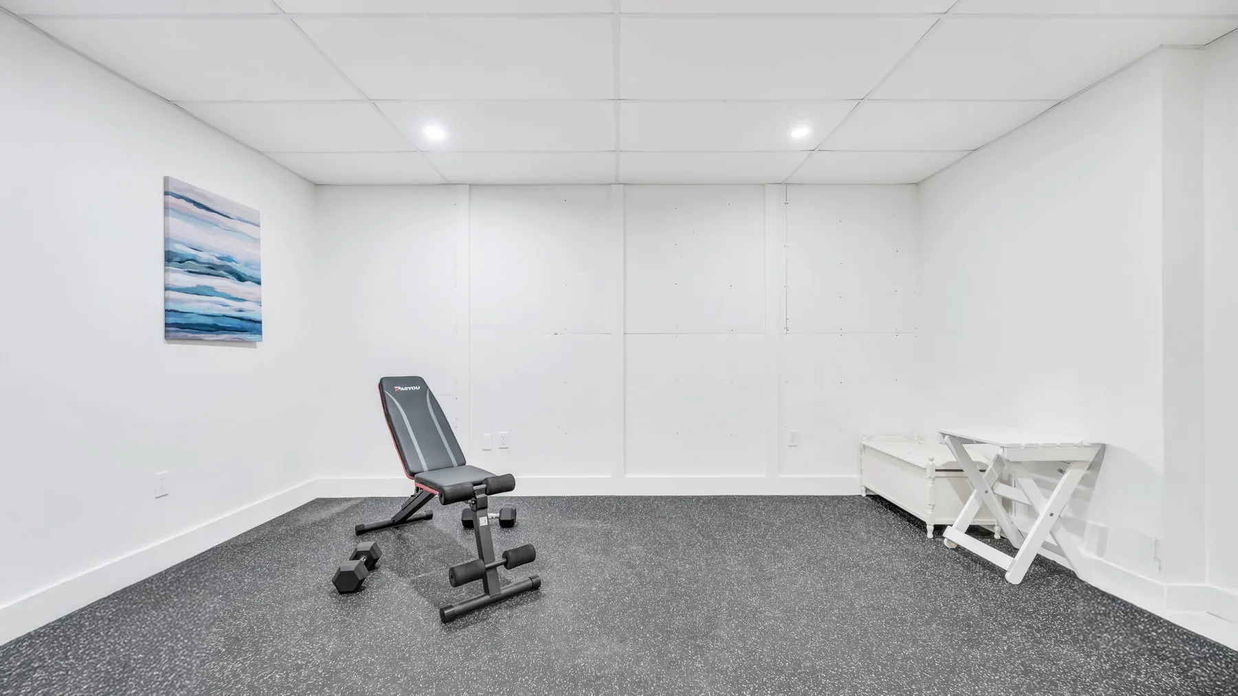 A small exercise room with an adjustable bench and weights.
