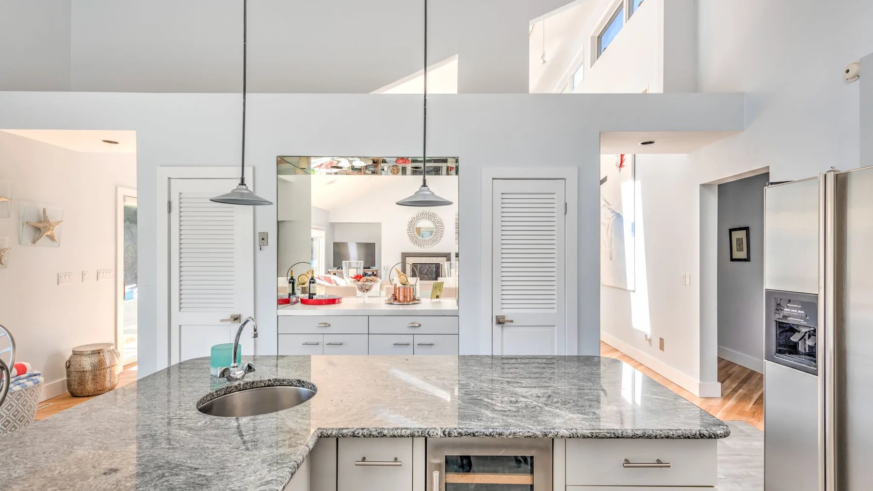 A bright kitchen with a large island and pendant lights.