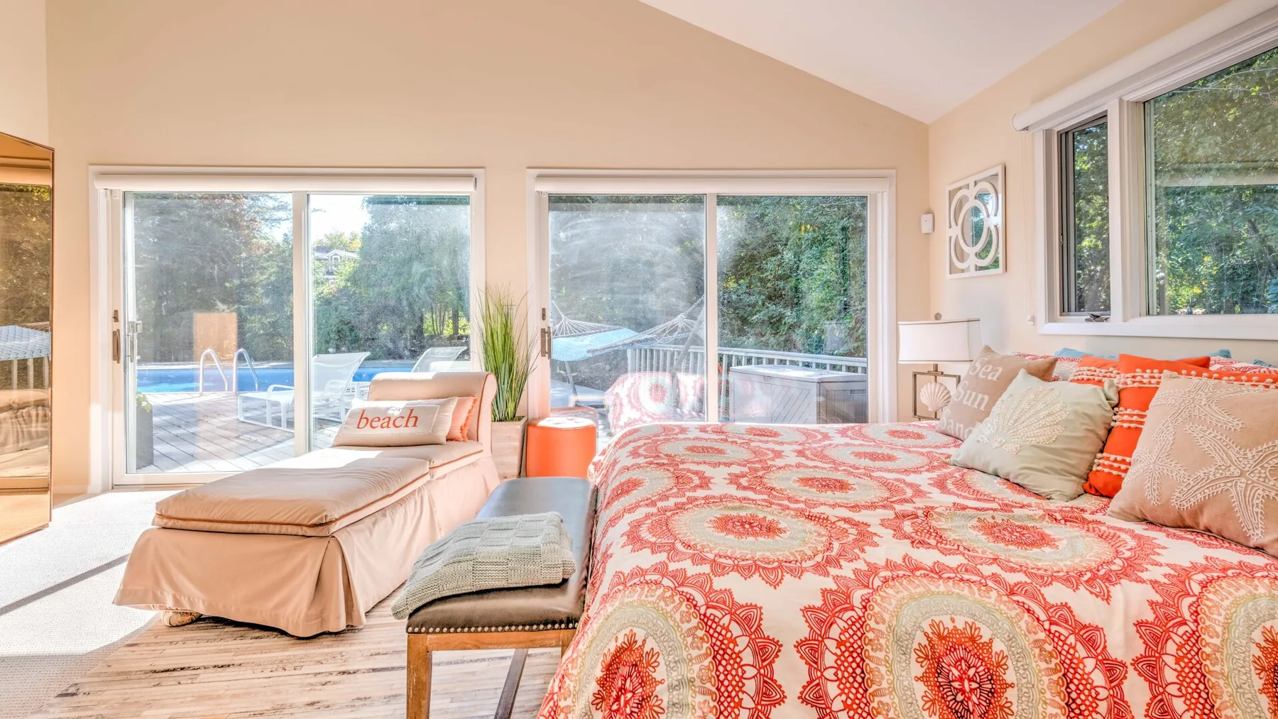 A bedroom with a large patterned bed and sliding glass doors opening toward a pool.