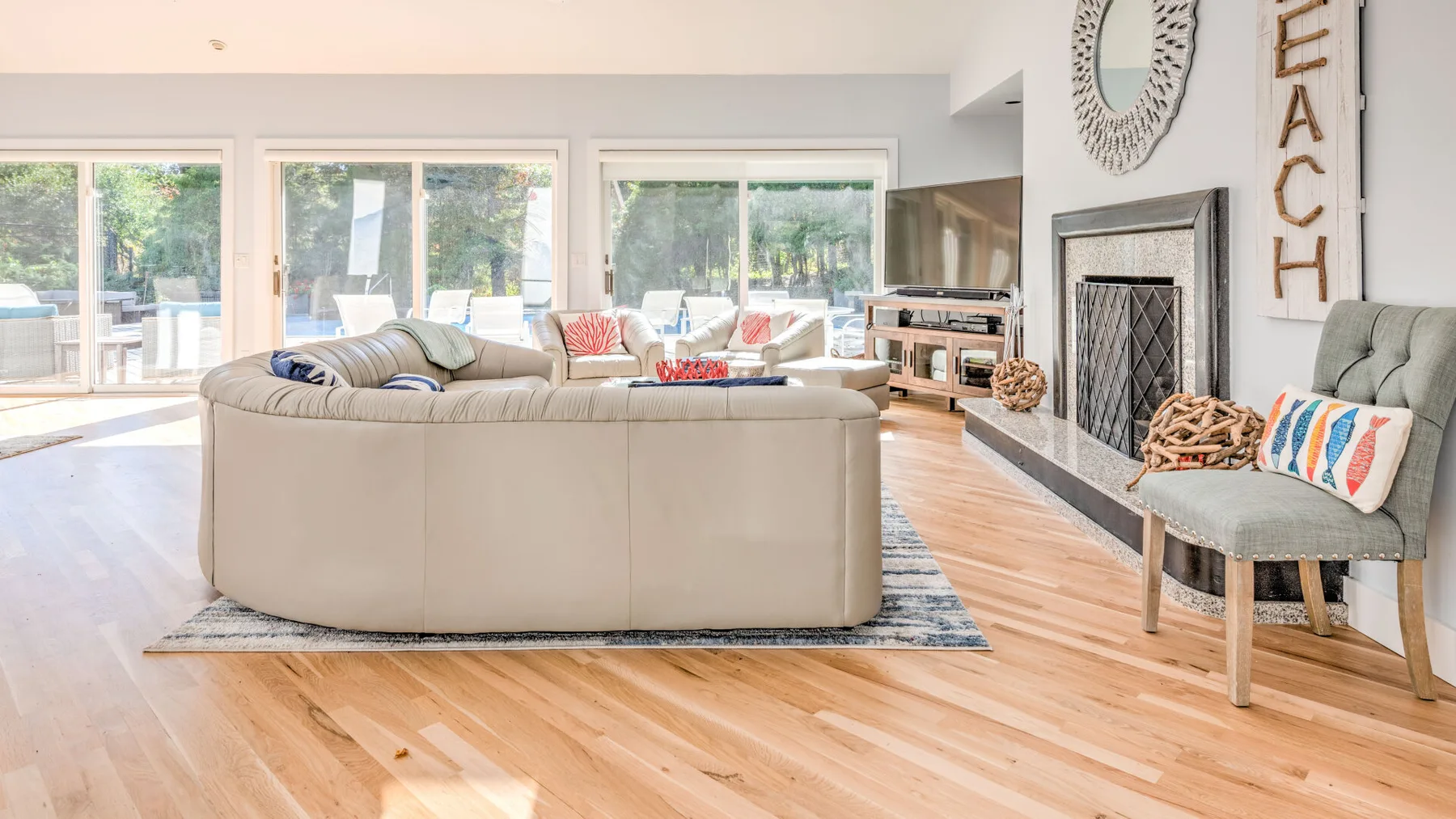 A bright living room with seating, large windows, and a fireplace.