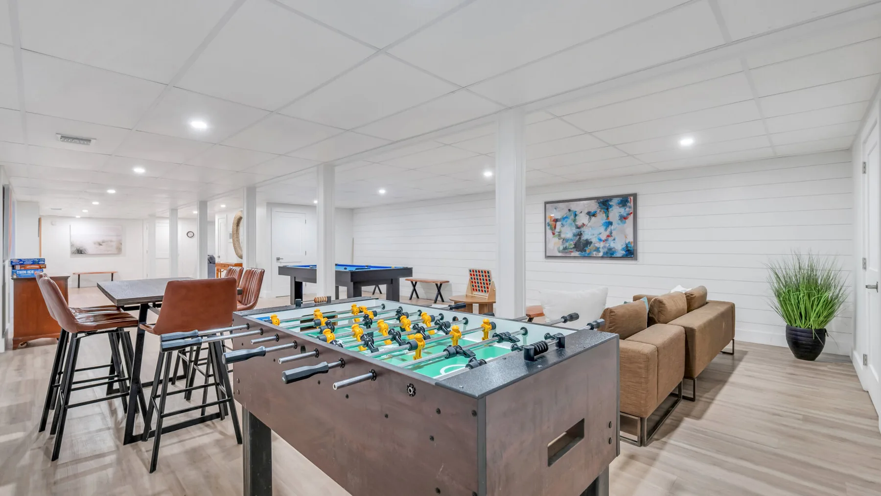 A recreation room with a foosball table, bar seating, and a couch.