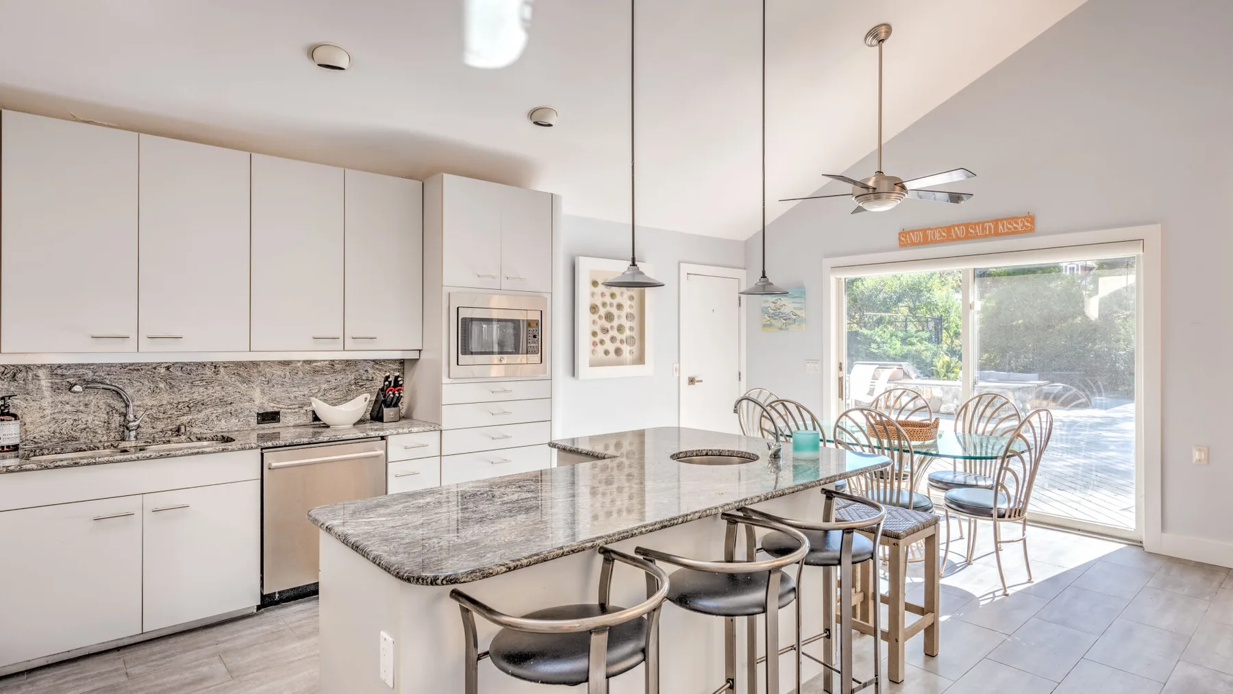 A bright kitchen and dining area opens onto a patio through large glass doors.
