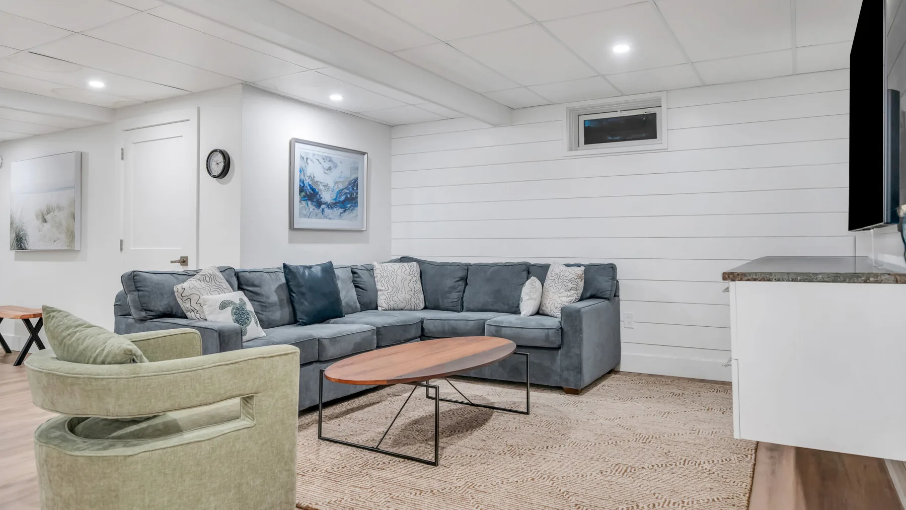 A living room with sectional seating, a coffee table, and wall art.