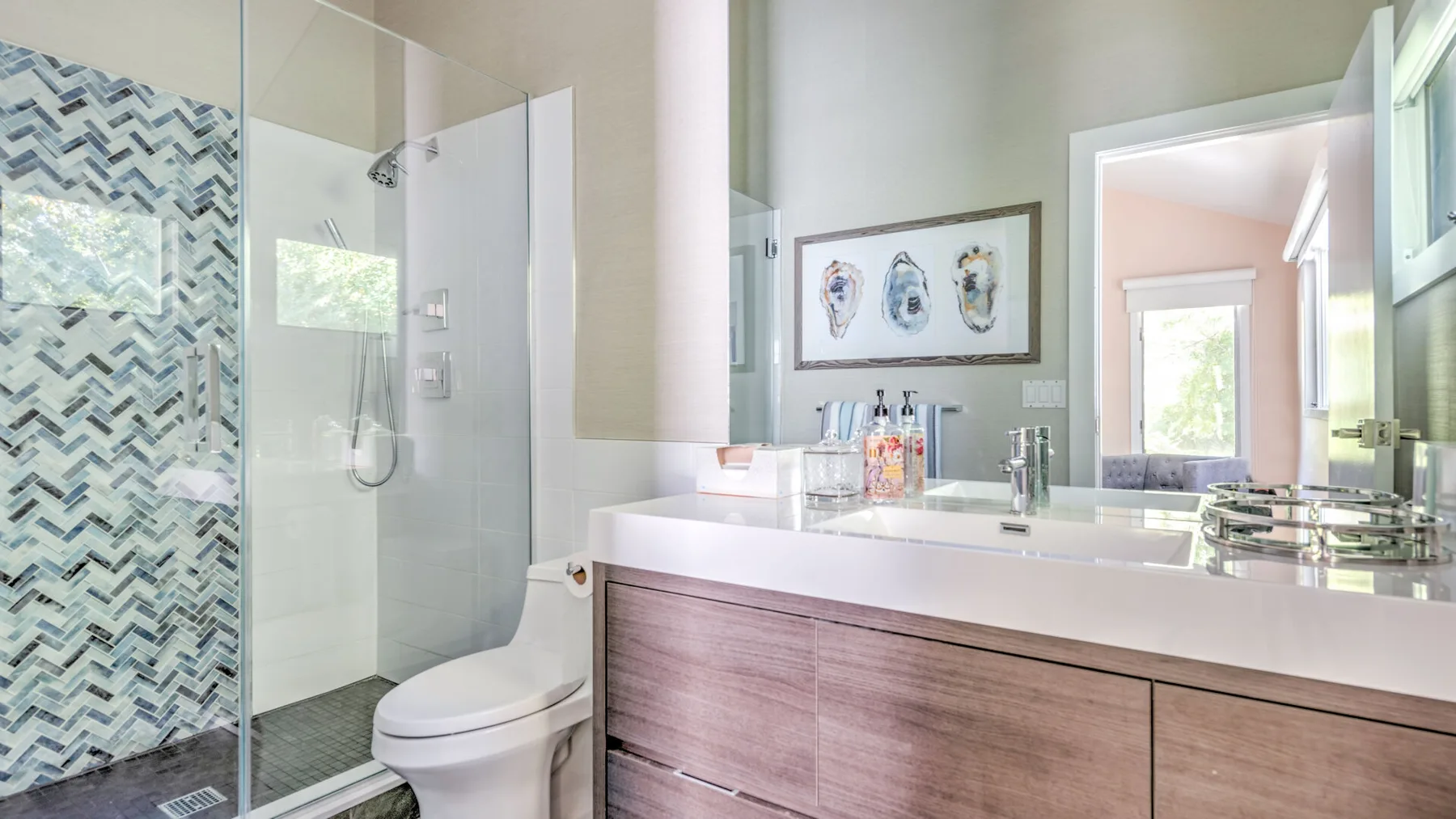 A bathroom with a glass shower, toilet, and wide vanity.