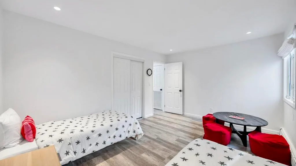 A bright bedroom has a star-patterned bed and a small table with red seating.