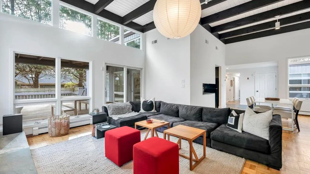 A bright living room with a large sectional seating area and tall windows.