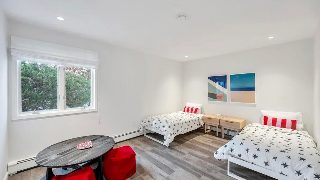 A bright bedroom with two beds, a window, and a small seating area.
