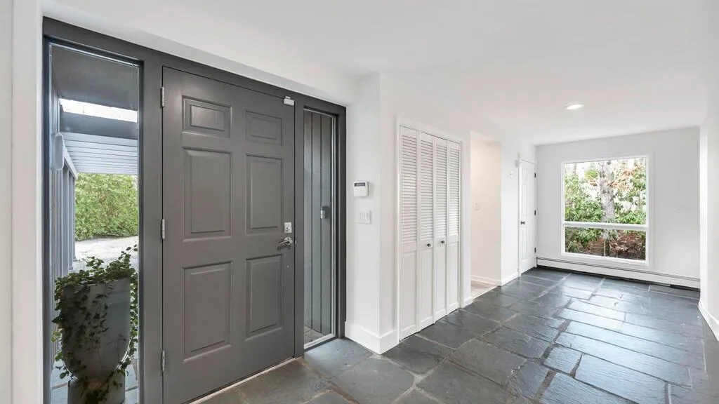 A bright entryway with a dark front door and a large window.