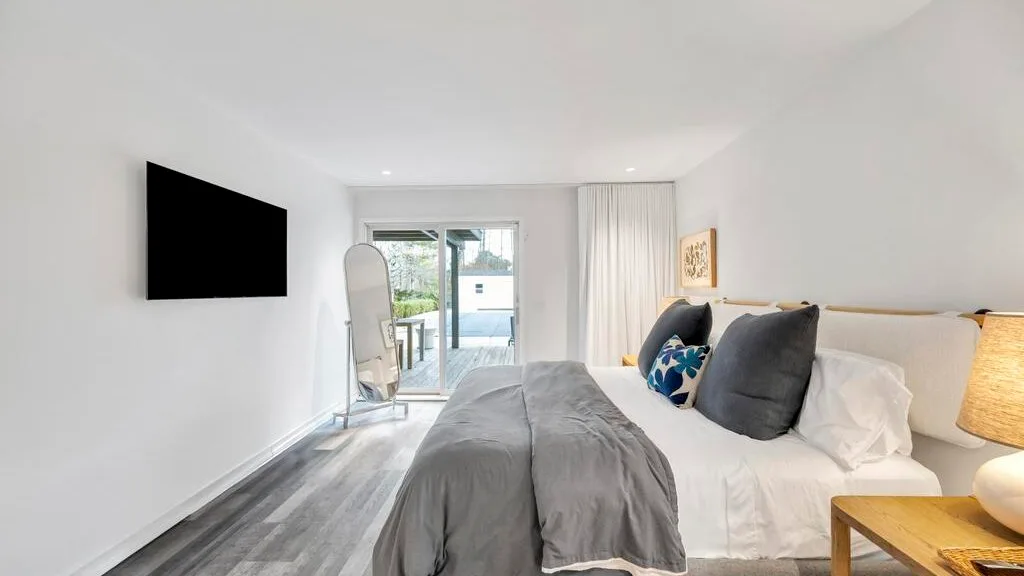 A bedroom with a neatly made bed and sliding glass doors opening onto a patio.