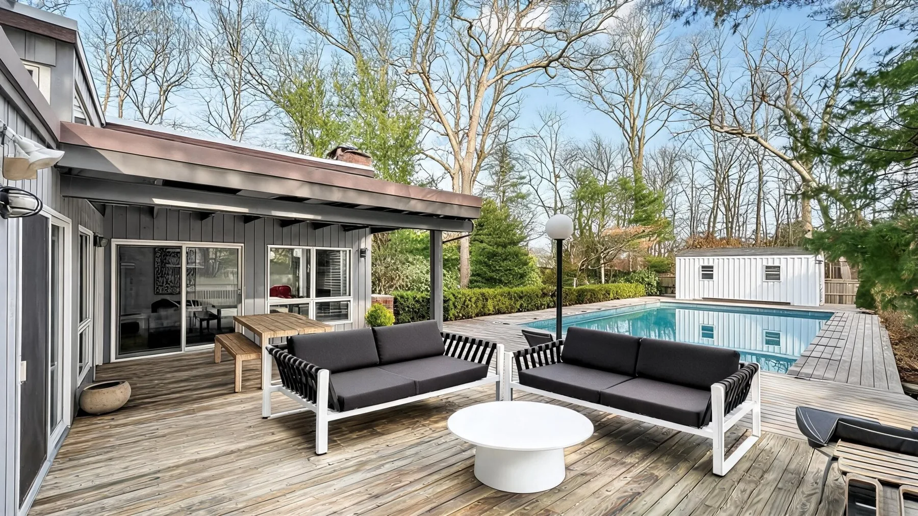 A wooden deck with outdoor seating overlooks a swimming pool.