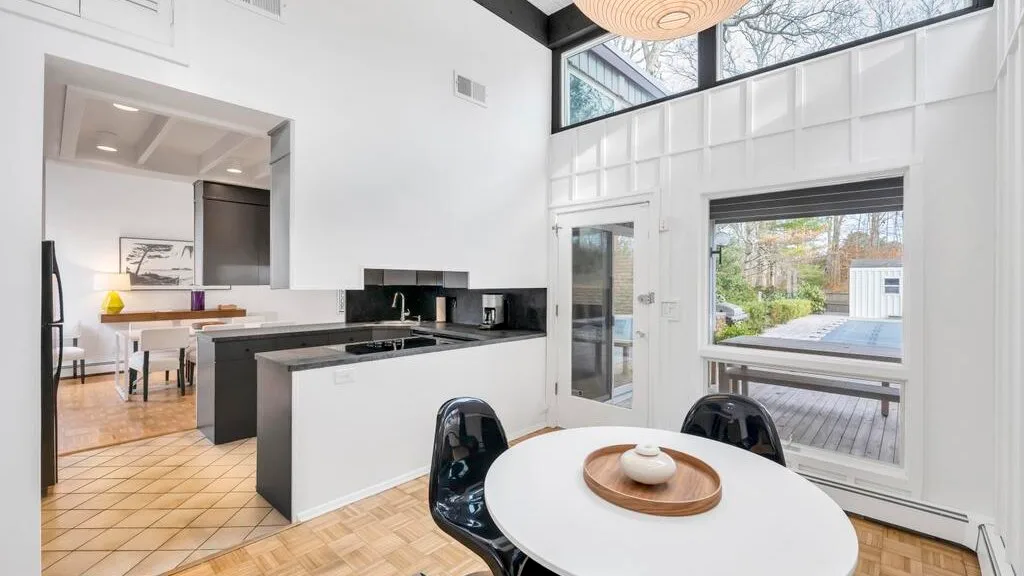 A bright open-plan kitchen and dining area opens onto a deck through large windows.
