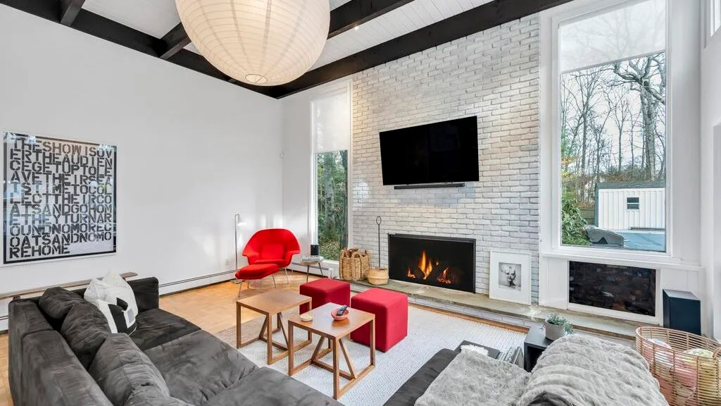 A bright living room with seating, a fireplace, and a wall-mounted television.
