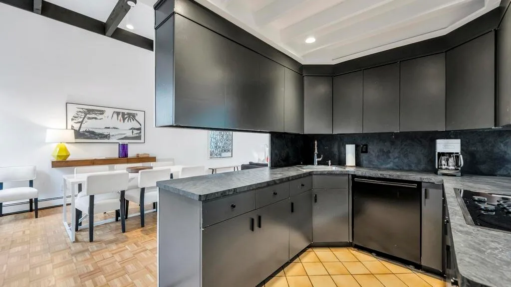 A modern kitchen with dark cabinets and a dining table beside the counter.