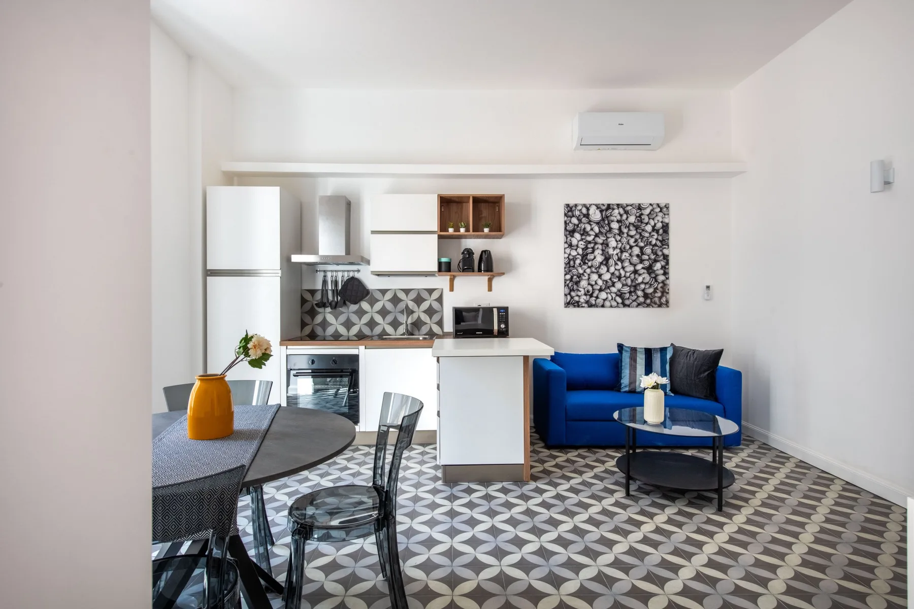 A compact open-plan living area combines a blue seating area with a small kitchen.