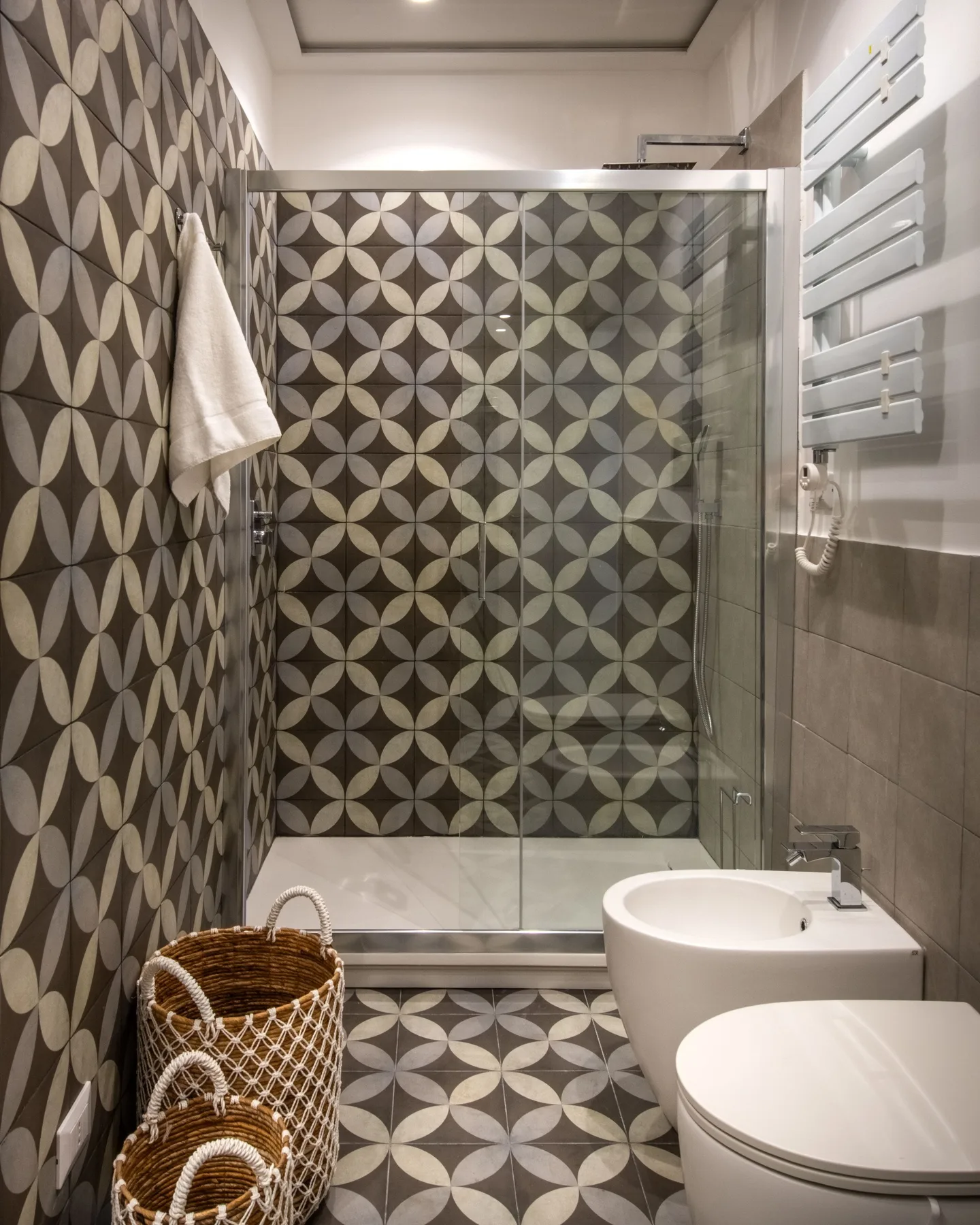 A tiled bathroom with a glass shower, sink, and toilet.