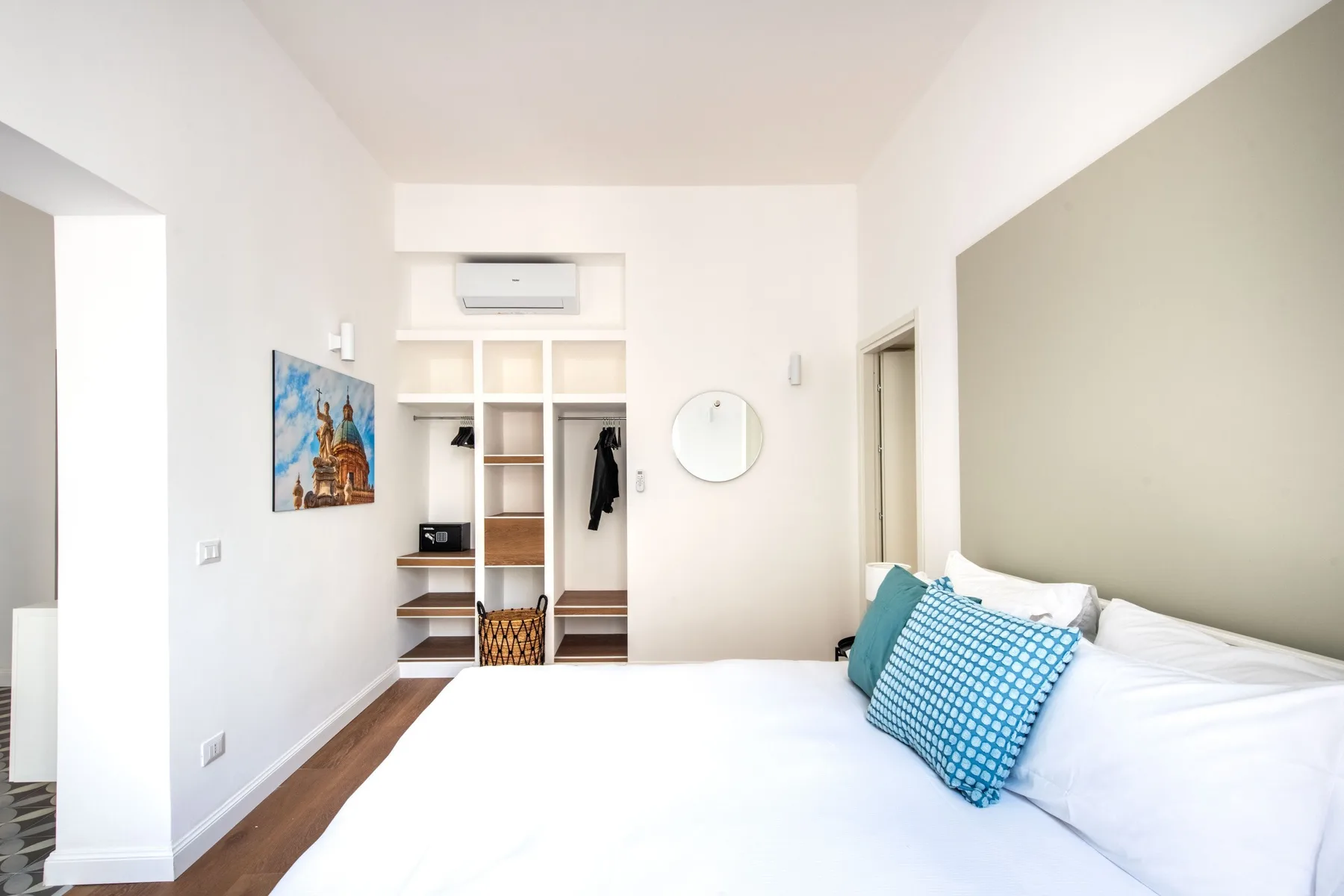 Bedroom with a bed, open wardrobe, and wall-mounted air conditioner.
