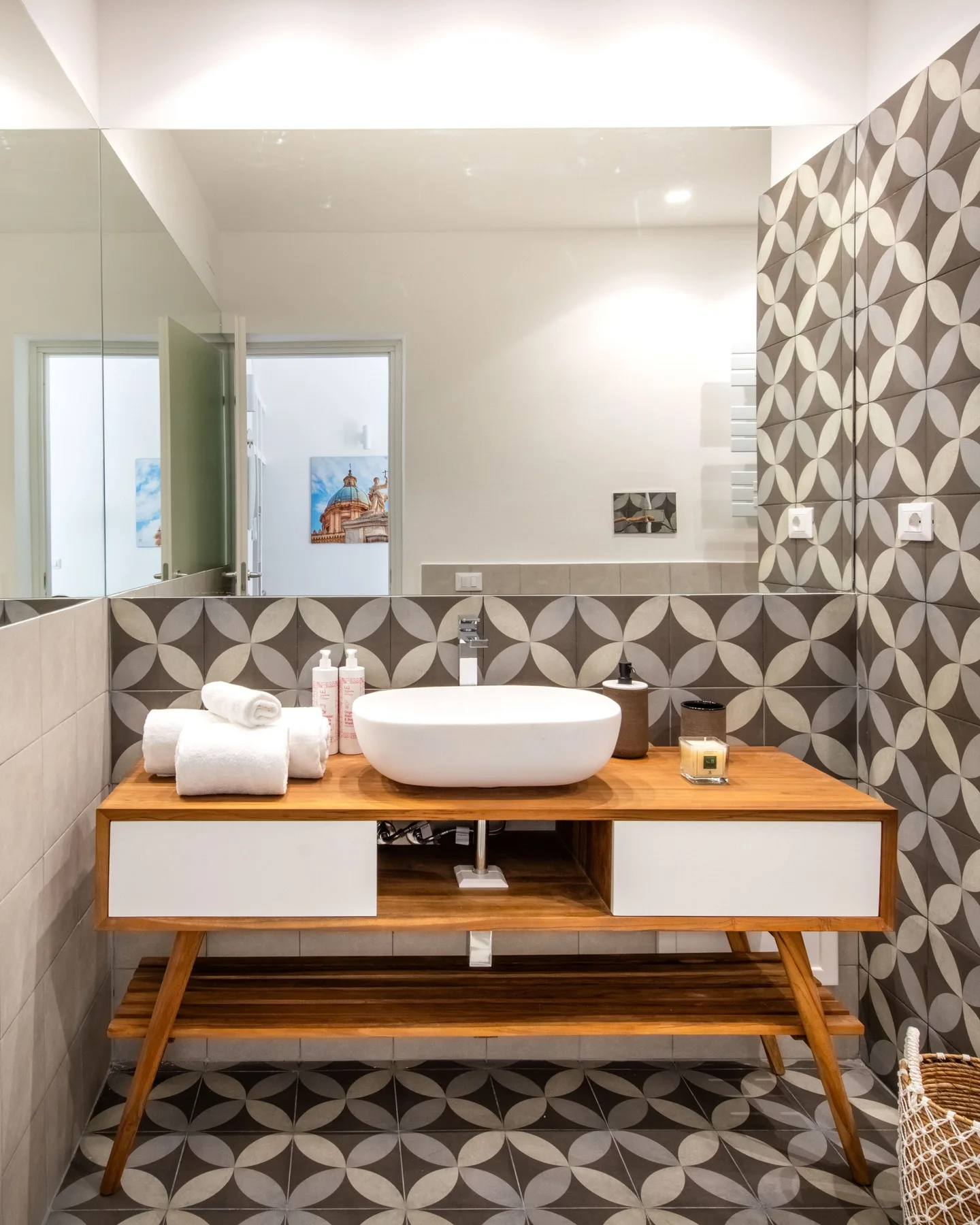 A bathroom vanity with a white basin stands against patterned tile.
