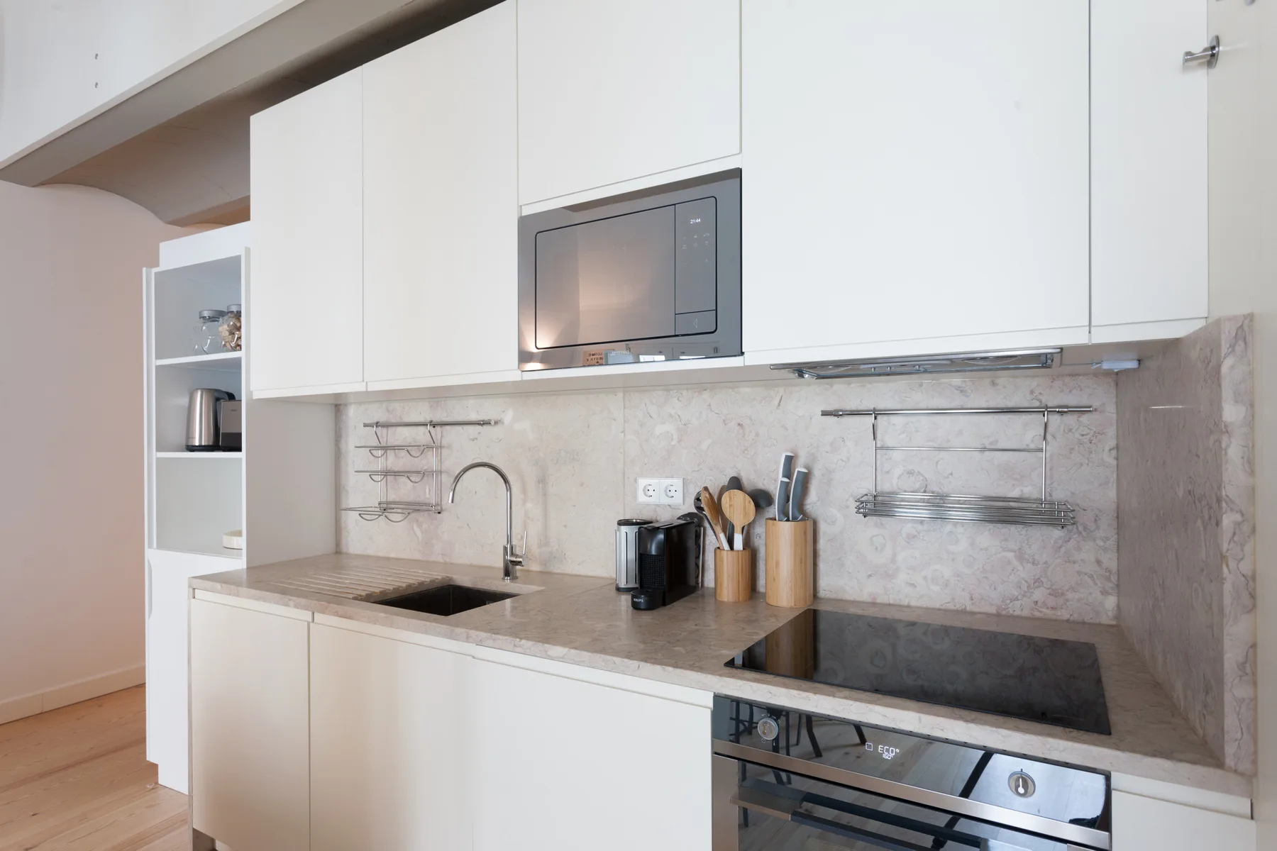 A modern kitchen with white cabinets, a countertop, and built-in cooking appliances.