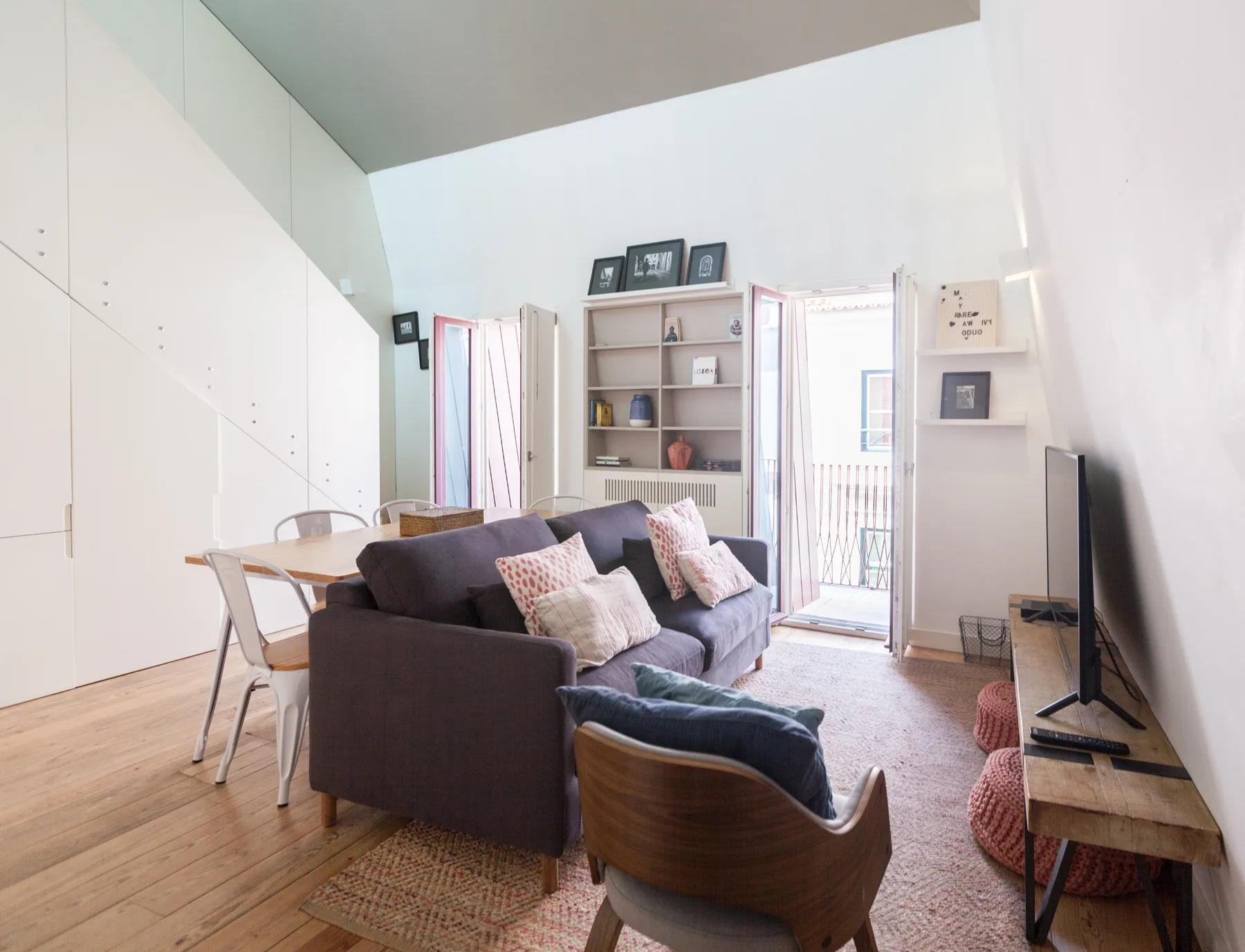 A bright living room with seating, a dining table, and a balcony door.
