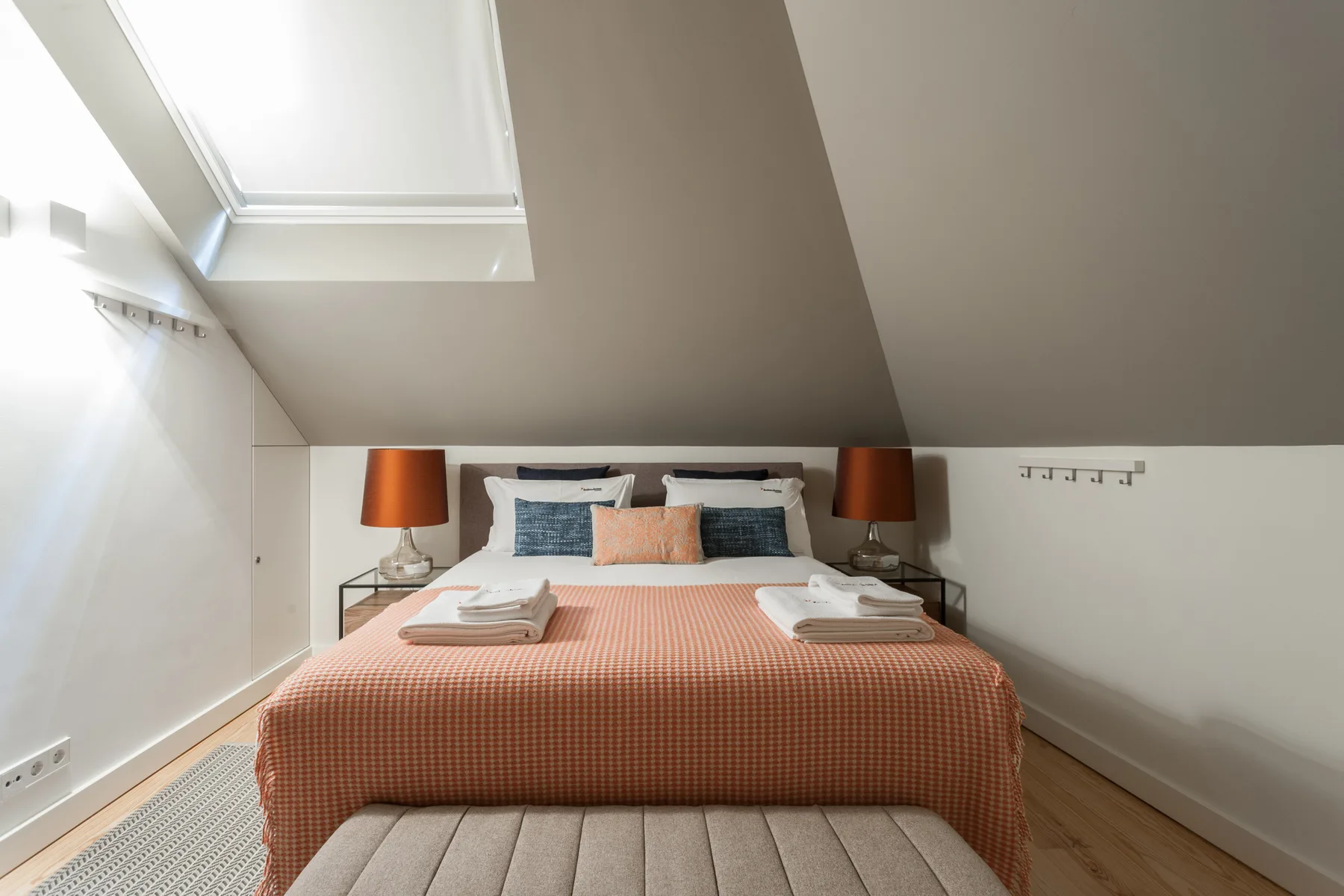 Un dormitorio con una cama bien tendida bajo un techo inclinado.