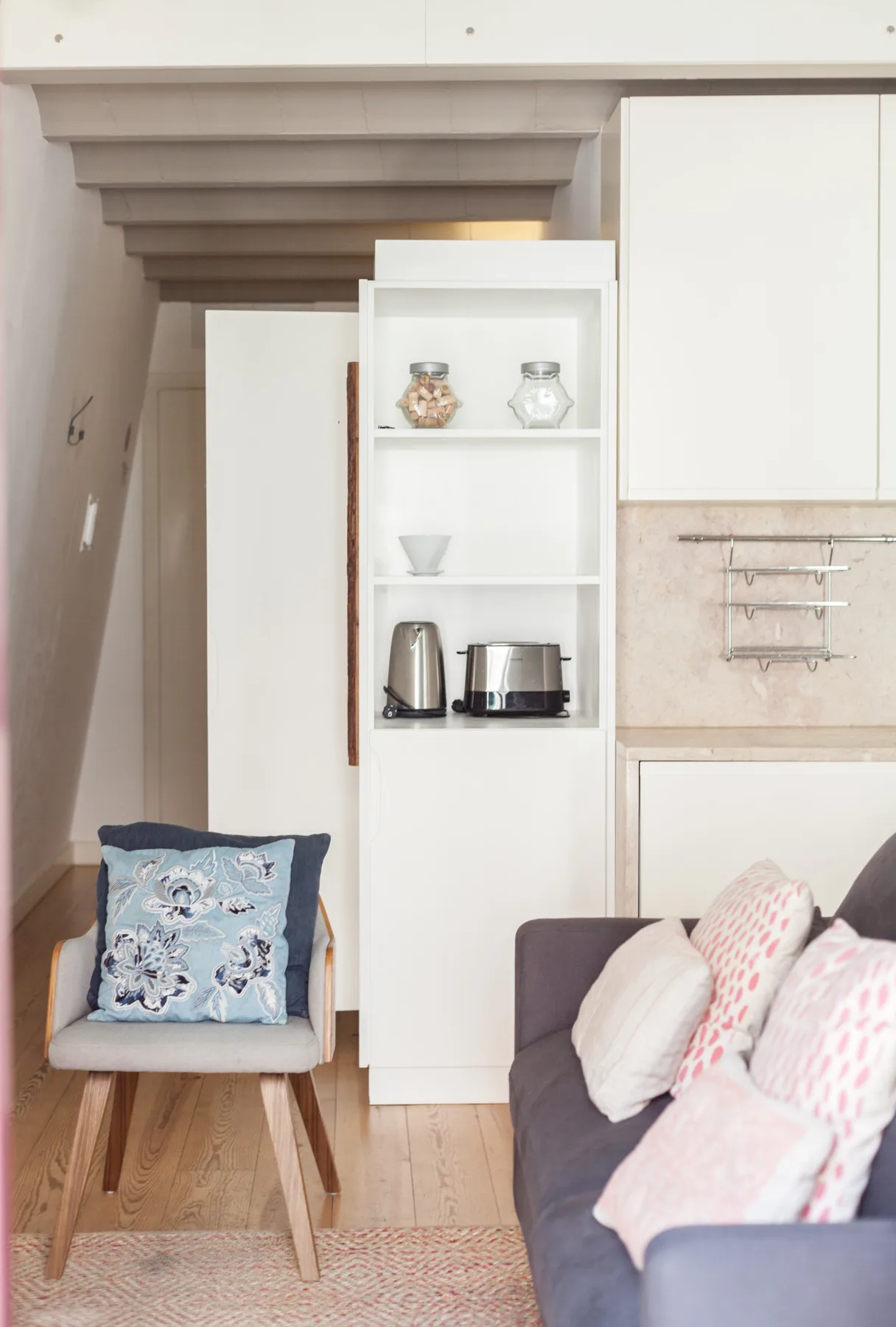 A living area with seating, cushions, and open shelving.
