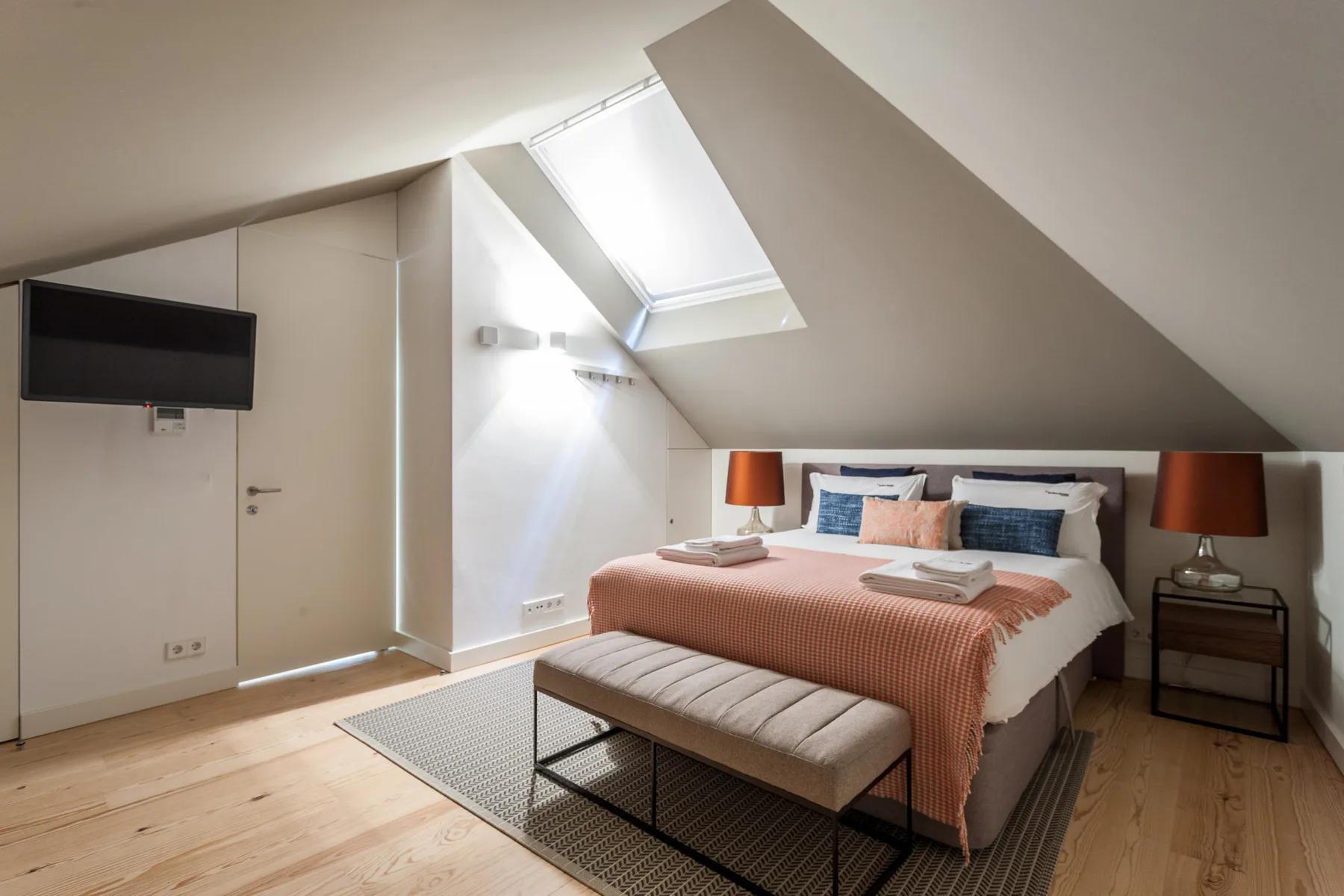 An attic bedroom with a bed beneath a skylight.