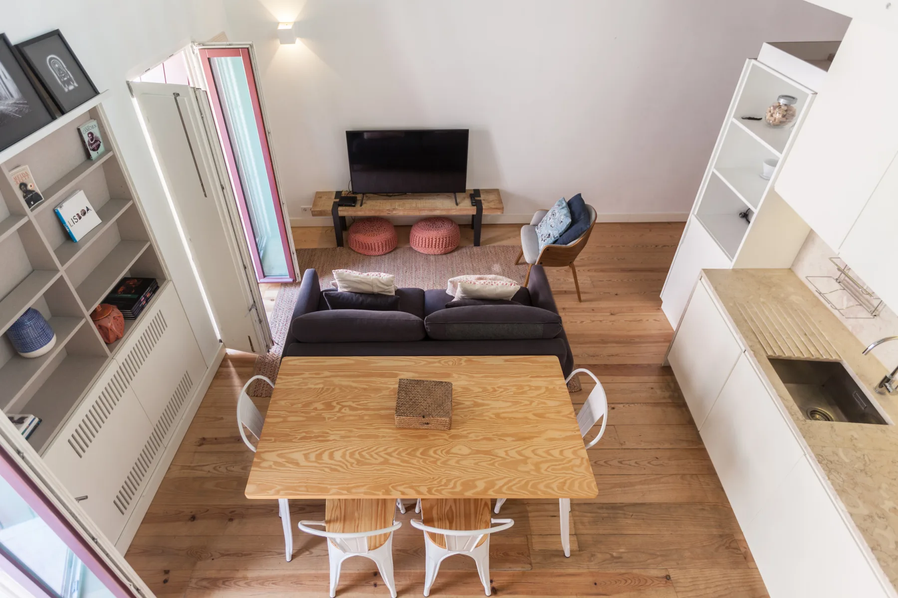 Una zona compacta de estar y comedor con sofá, televisor y mesa de madera.