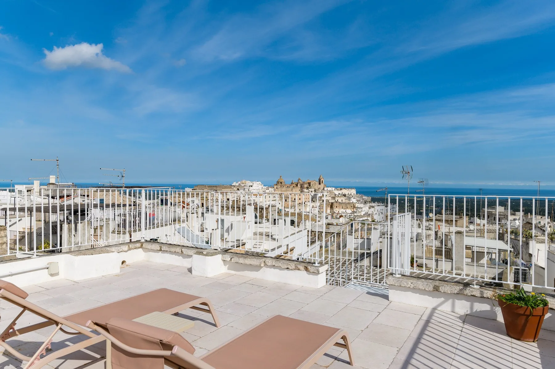 Una terraza en la azotea tiene tumbonas y vistas de la ciudad y el mar.