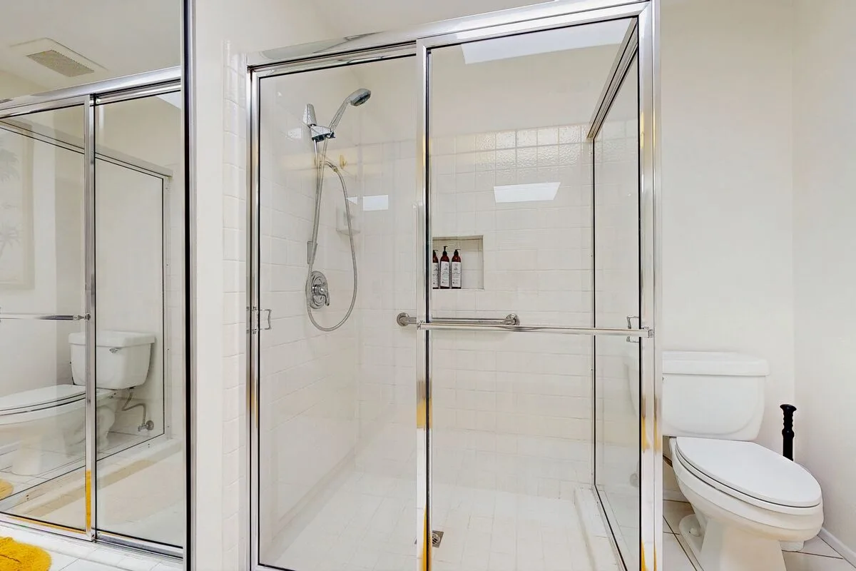 A bathroom with a glass-enclosed shower and toilet.