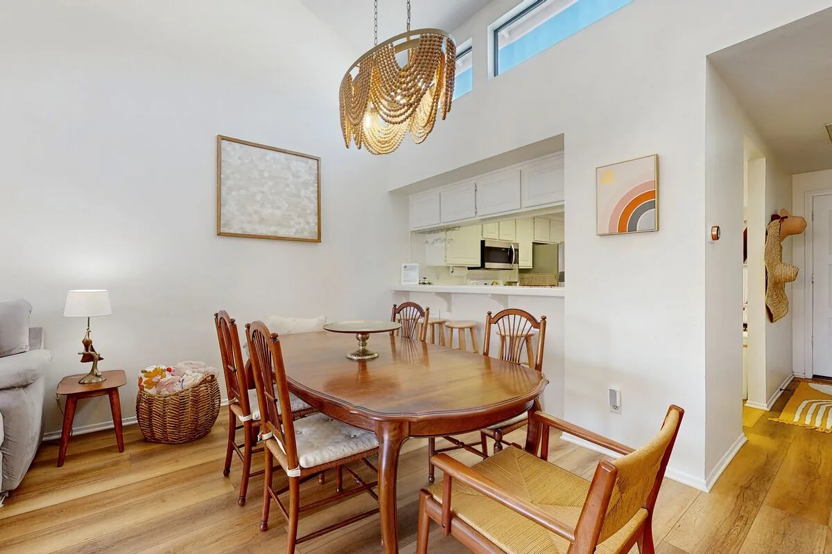 A dining area with a wooden table and chairs beside an open kitchen.