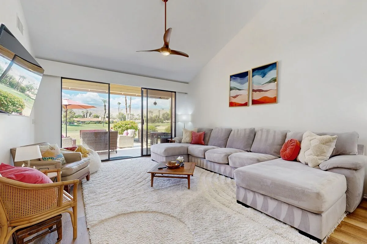 A bright living room with sectional seating and sliding glass doors opening onto a patio.