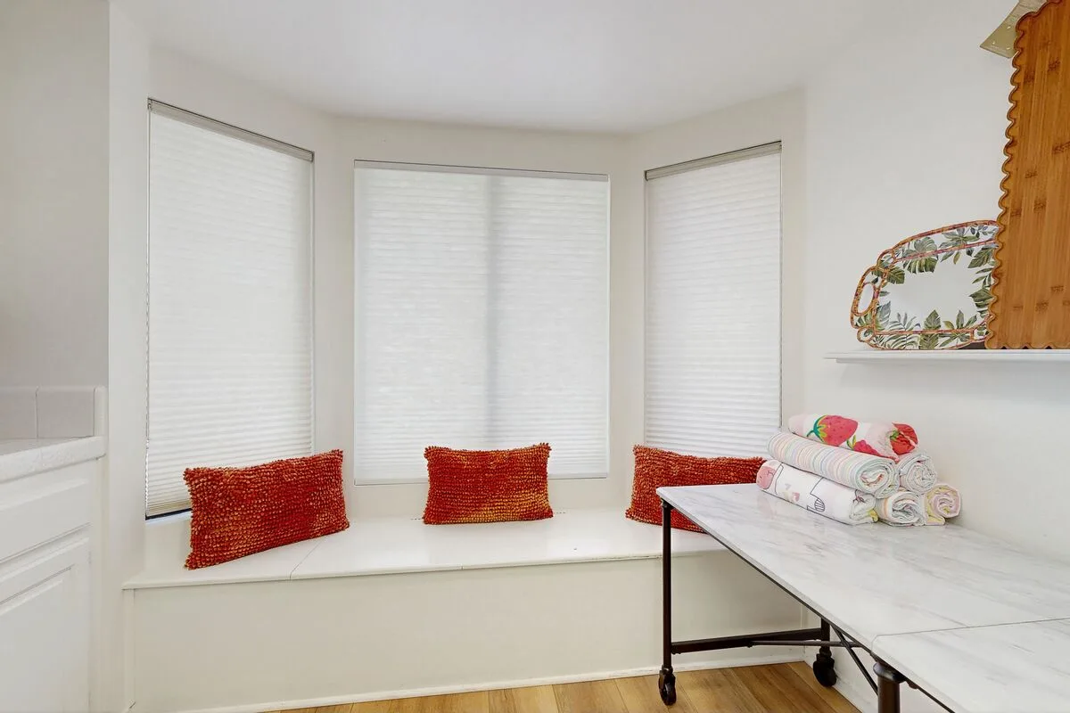 A bright room with a built-in window seat and a worktable.