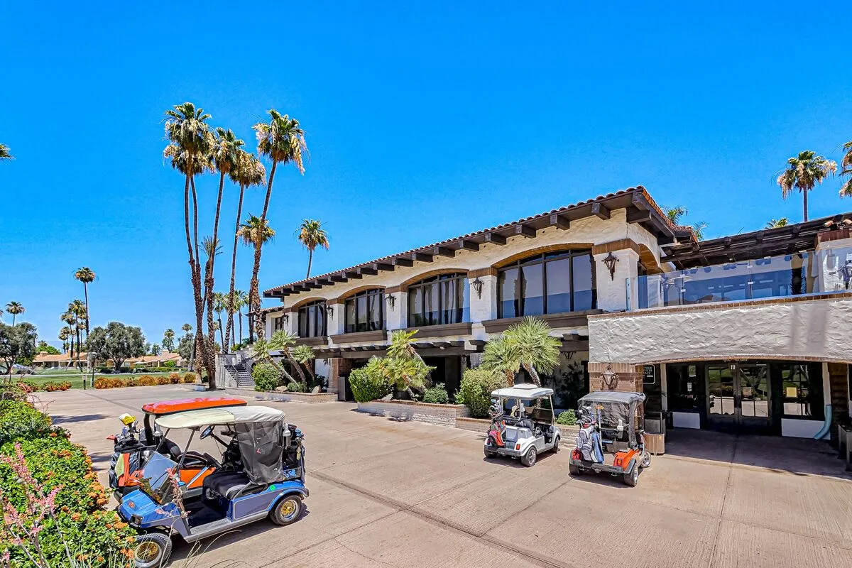 A large building with palm trees and several golf carts parked in front.