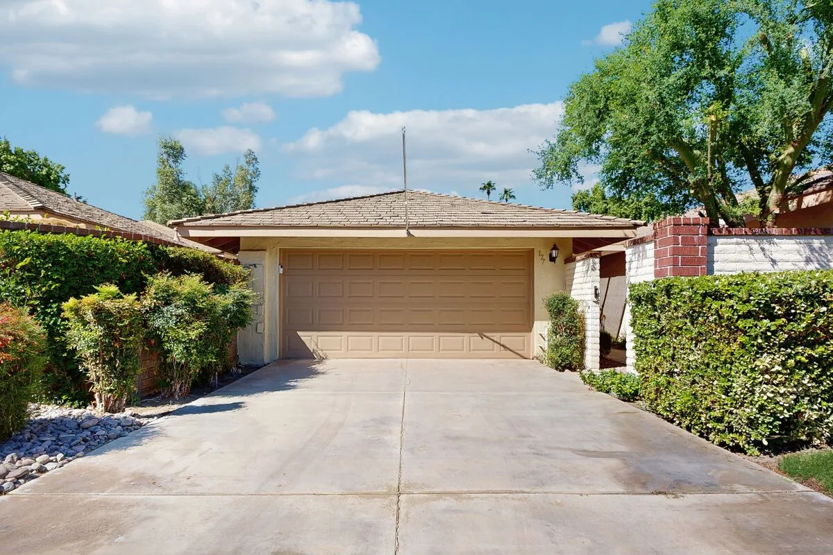 A house exterior with a wide driveway leading to a closed garage door.
