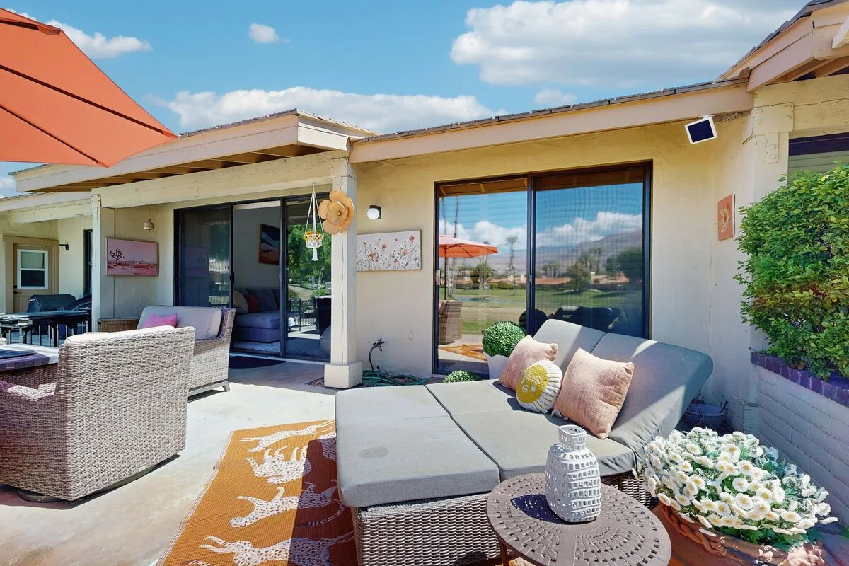 An outdoor patio seating area with cushioned furniture and a garden view.