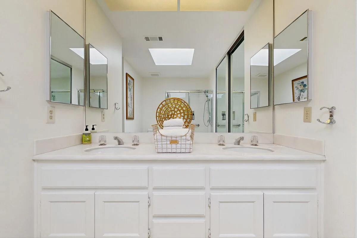 A bathroom vanity with two sinks and mirrored walls.