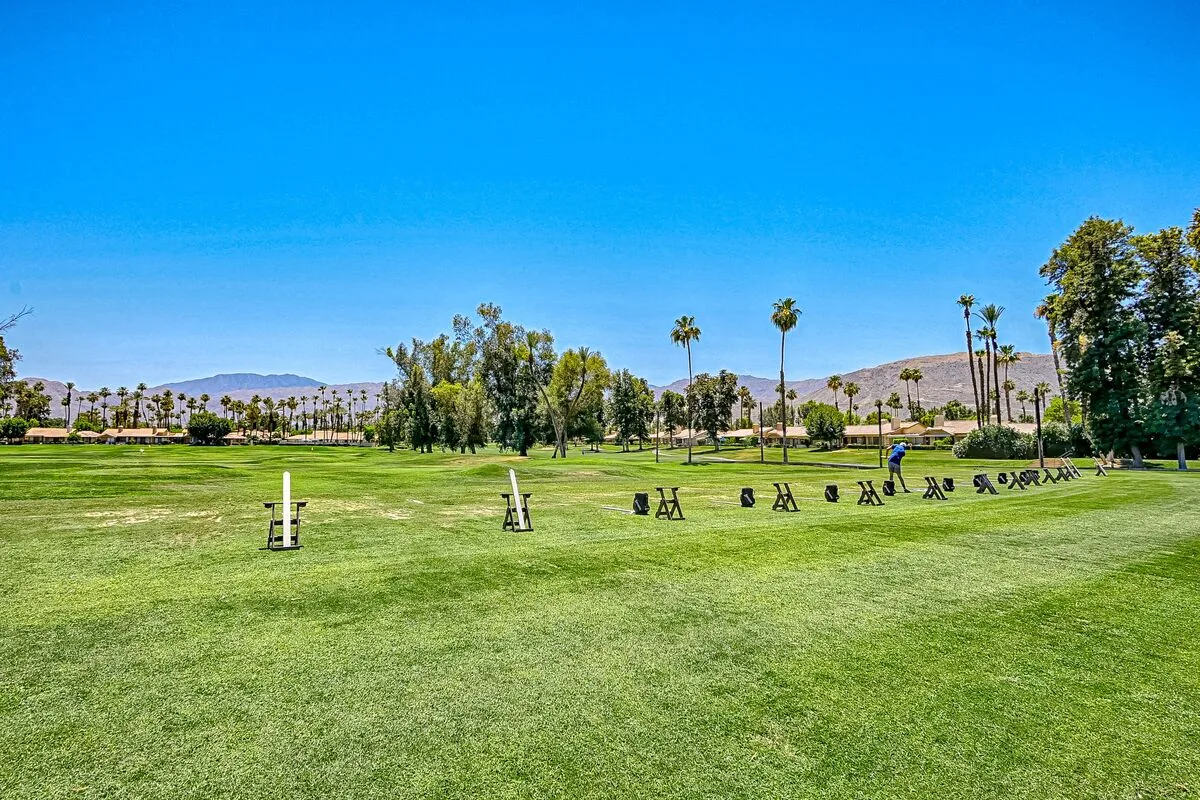 A broad green lawn with scattered exercise equipment beneath a clear blue sky.