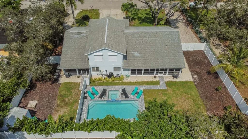 An aerial view shows a house with a rectangular swimming pool in the yard.
