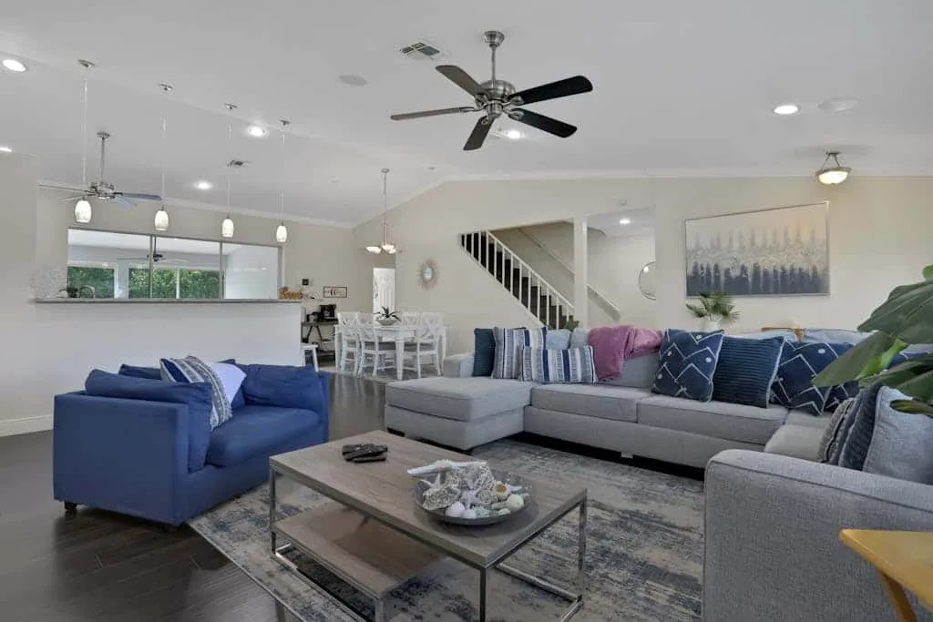 A spacious living room with blue and gray seating around a coffee table.