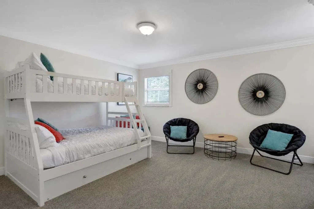 A bedroom with a white bunk bed and two chairs around a small table.