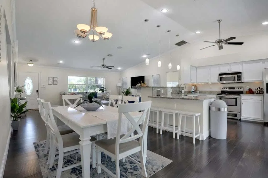A bright open-plan dining and kitchen area with a long island and white seating.