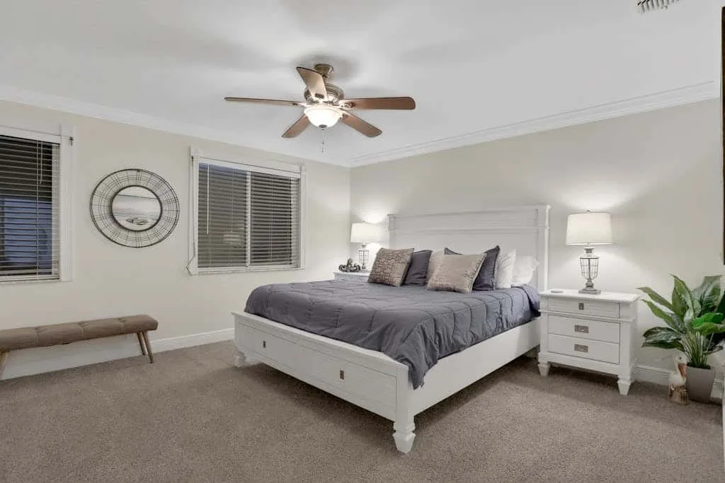 A bedroom with a bed, matching bedside tables, and a ceiling fan.