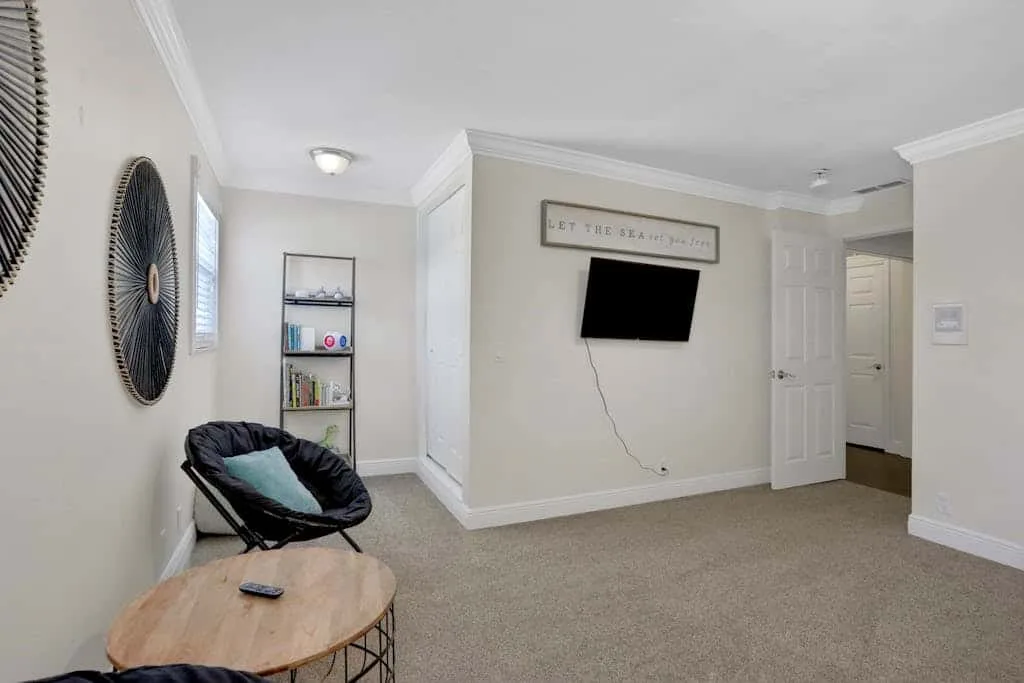 A sitting area with a wall-mounted television and a chair beside a small table.