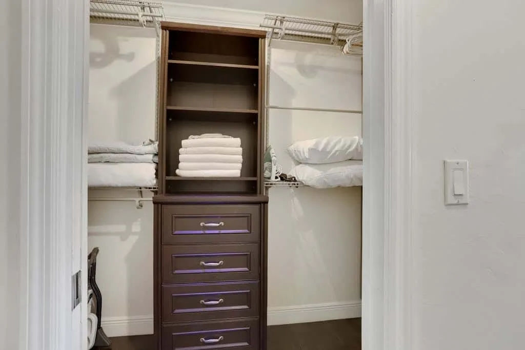 A walk-in closet with open shelving and folded linens.